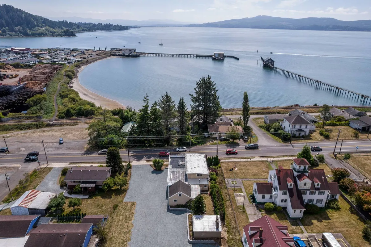 This image shows the waterfront near the property, featuring the public pier, calm waters, and surrounding hills. The scene is serene, with people fishing, boats nearby, and families walking along the shore, showcasing direct access to outdoor coastal activities.