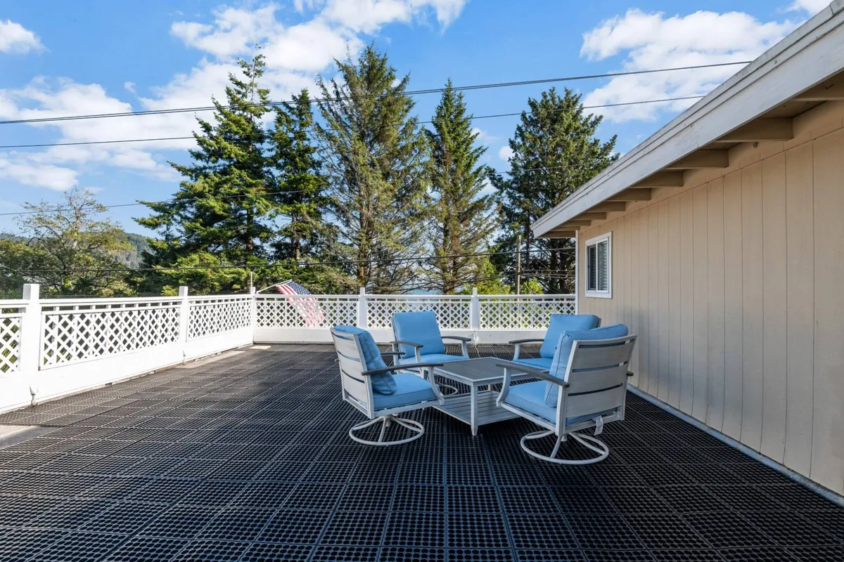 A tranquil patio area with comfortable furniture and surrounding trees, enclosed by a fence. The setting exudes relaxation, ideal for unwinding after a day outdoors, sharing stories, or enjoying an evening meal with friends or family.